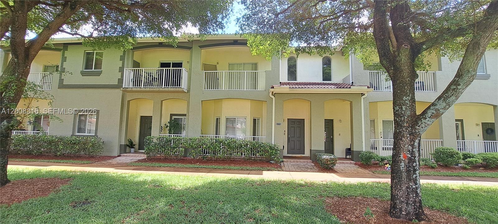 A two-story townhouse exterior features a light green facade, white railings, and arched windows — 1978 SE 23rd Ter, Homestead FL 33035, HOMESTEAD, FL