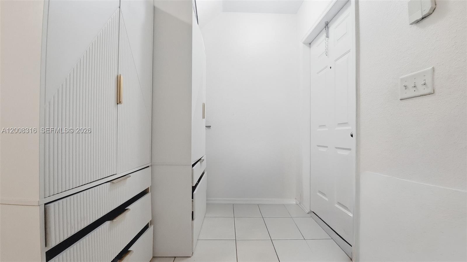 A hallway features white cabinetry with gold hardware, tiled flooring, and a white door — 1978 SE 23rd Ter, Homestead FL 33035, HOMESTEAD, FL
