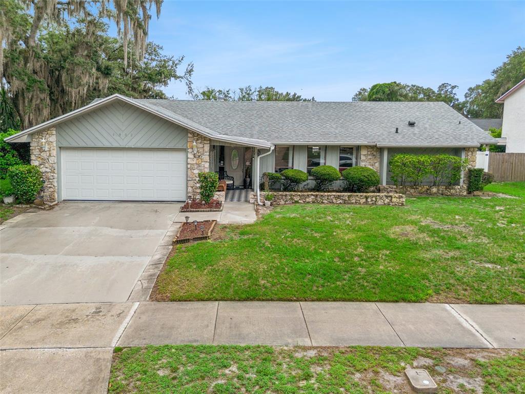 A single-story house with a stone facade, gray siding, and a two-car garage — 4902 BRIAR OAKS CIRCLE, ORLANDO, FL
