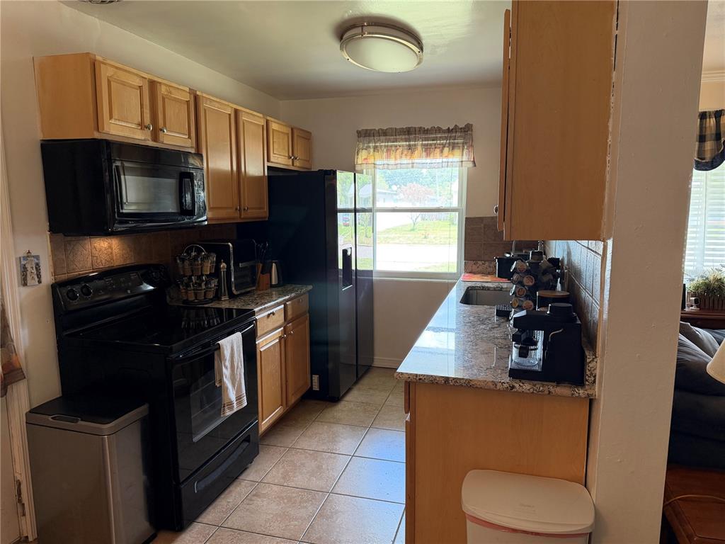 A kitchen features light wood cabinets, black appliances, granite countertops, and tiled flooring — 616 DIAL DRIVE, ORLANDO, FL