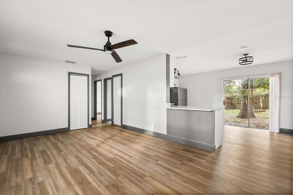 An open-concept living area features wood-look flooring, a ceiling fan, and a kitchen pass-through window — 2507 NEWBERRY STREET, ORLANDO, FL