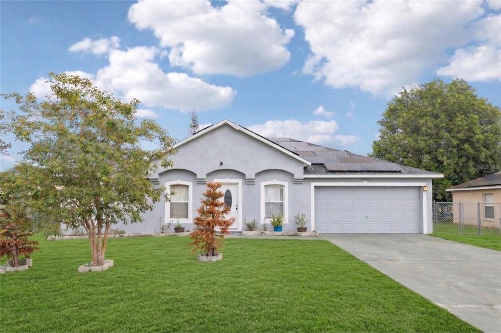 A single-story gray house with a two-car garage and solar panels on the roof — 42 INCONNU DR, POINCIANA, FL