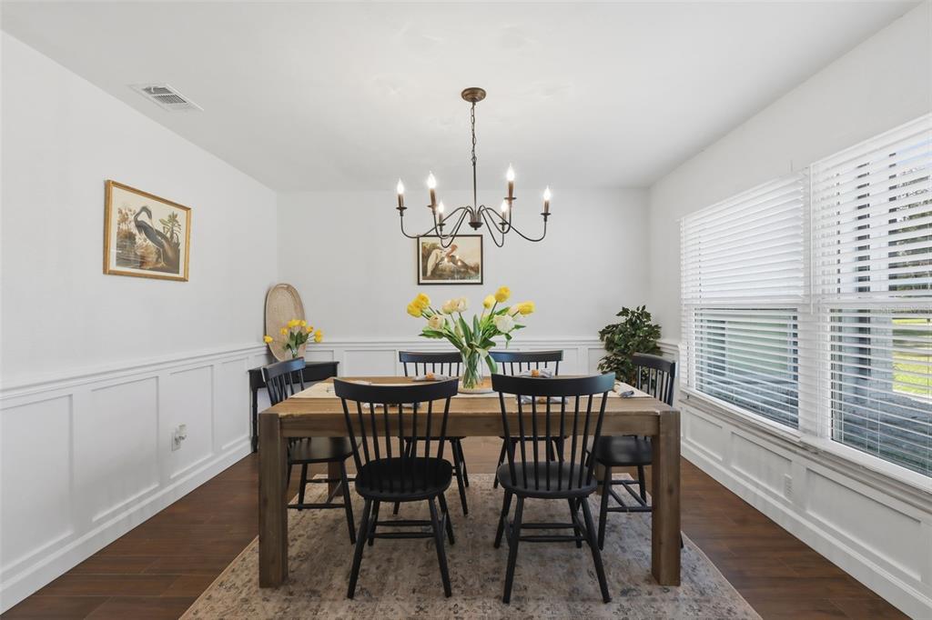 A dining room features a wooden table, black spindle chairs, wainscoting, and a chandelier — 155 E COUNTRY CIRCLE DRIVE E, PORT ORANGE, FL