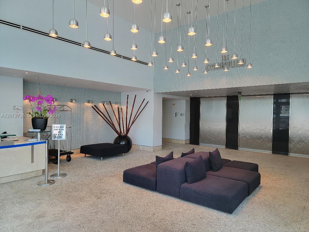 A modern building lobby features a large seating area, hanging pendant lights, and decorative art — 110 Washington Ave # 2310, Miami Beach FL 33139, MIAMI BEACH, FL