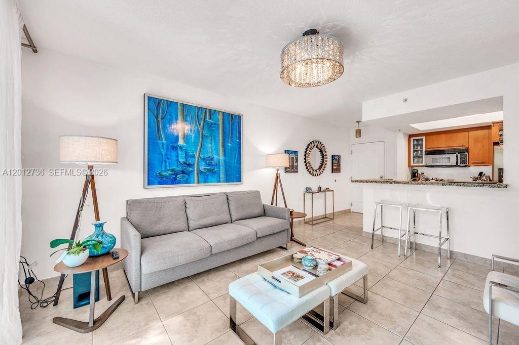 A living room features a gray sofa, a blue abstract painting, and a kitchen bar — 110 Washington Ave # 2310, Miami Beach FL 33139, MIAMI BEACH, FL