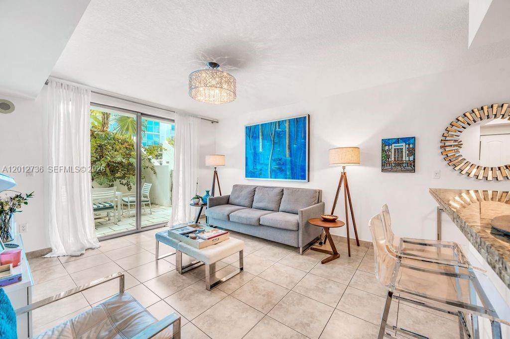 A living room features a gray sofa, a coffee table, and a sliding glass door — 110 Washington Ave # 2310, Miami Beach FL 33139, MIAMI BEACH, FL