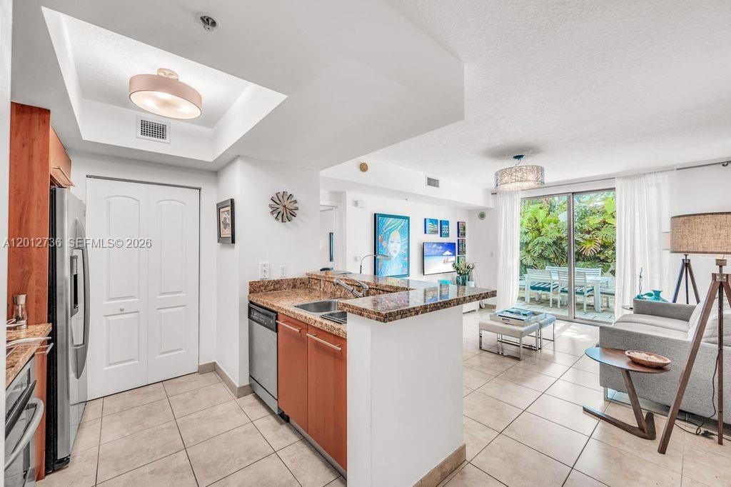 A kitchen with granite countertops and stainless steel appliances opens into a bright living area — 110 Washington Ave # 2310, Miami Beach FL 33139, MIAMI BEACH, FL