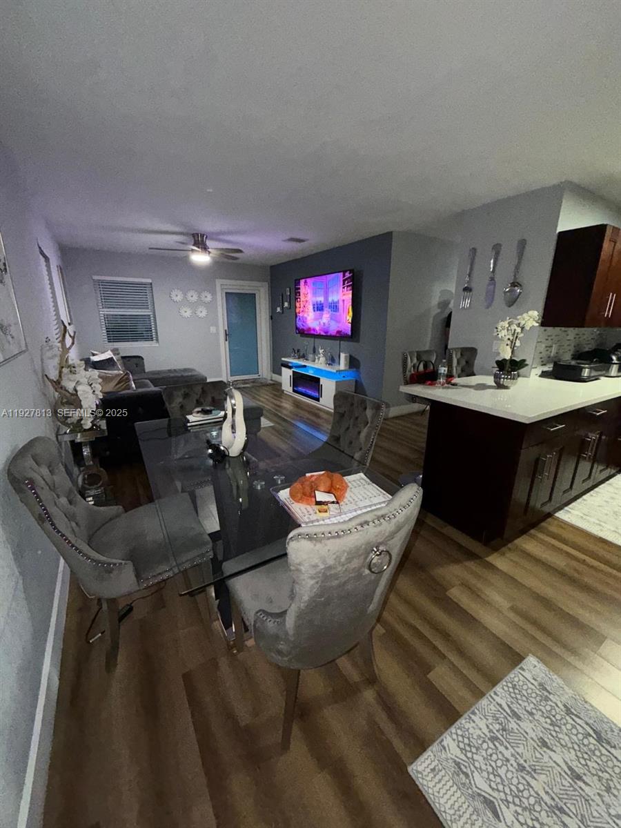 A dining area with a glass table and grey chairs sits adjacent to a kitchen — 100 NE 171st Ter, Miami FL 33162, MIAMI, FL
