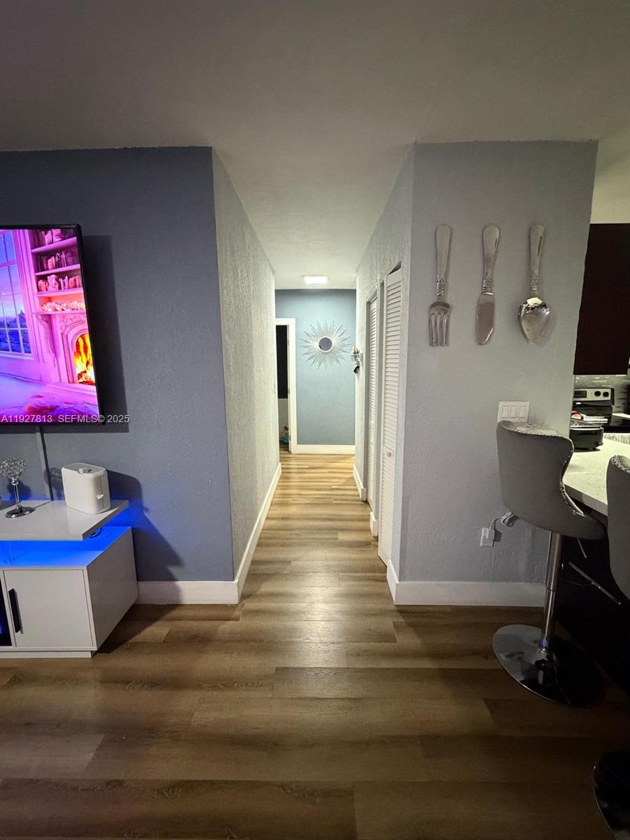 A hallway with wood-look flooring connects a living area to a back room — 100 NE 171st Ter, Miami FL 33162, MIAMI, FL