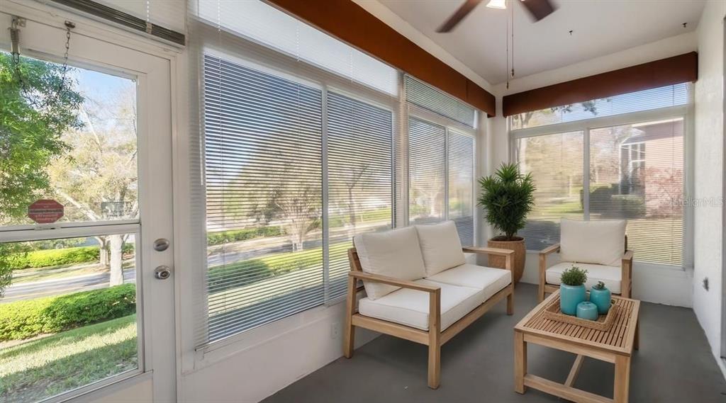 A sunroom with white furniture, a wooden coffee table, and large windows with horizontal blinds — 3734 HASTING LANE, CLERMONT, FL