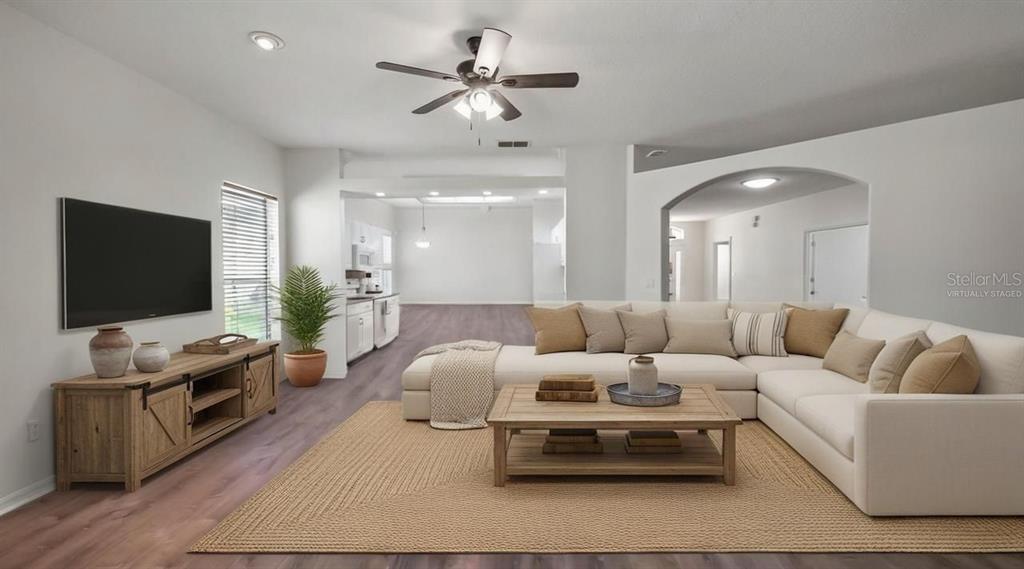 A living room with a sectional sofa, wooden coffee table, and media console on flooring — 3734 HASTING LANE, CLERMONT, FL