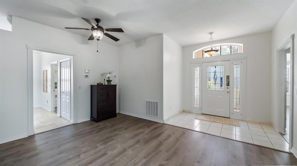An entryway with tiled flooring, a white front door with sidelights, and an adjacent living area — 3734 HASTING LANE, CLERMONT, FL