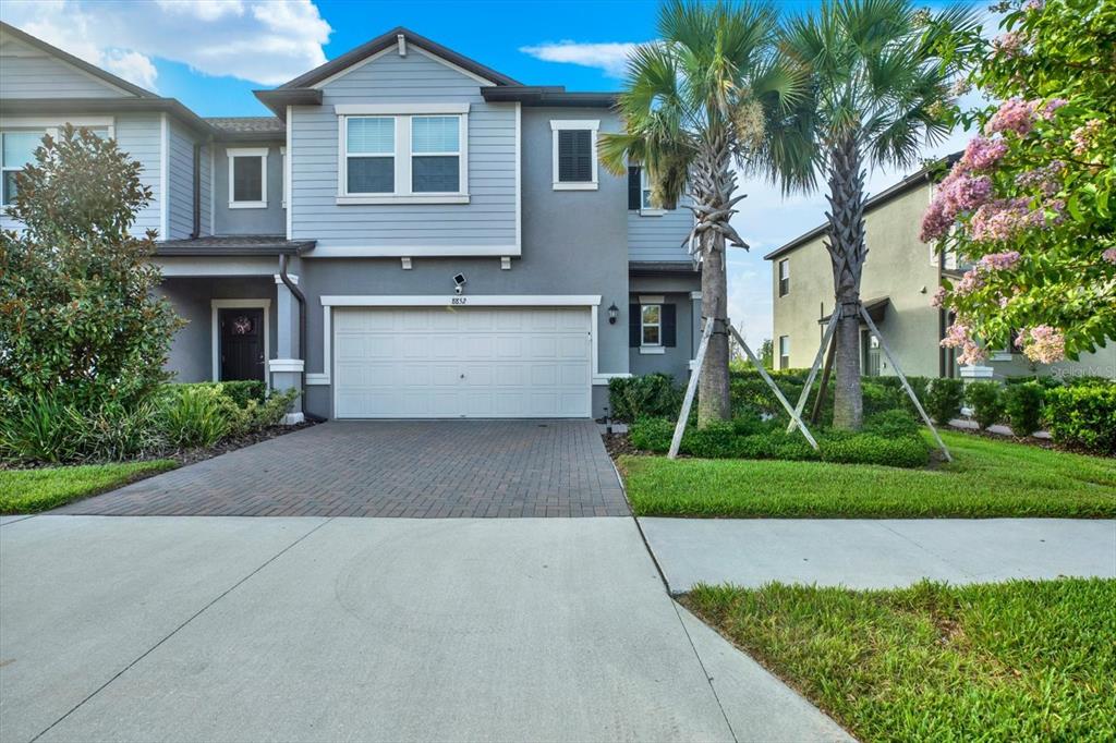 A two-story townhouse with a gray exterior, a two-car garage, and a paved driveway — 8852 GALLANTREE PLACE, LAND O LAKES, FL