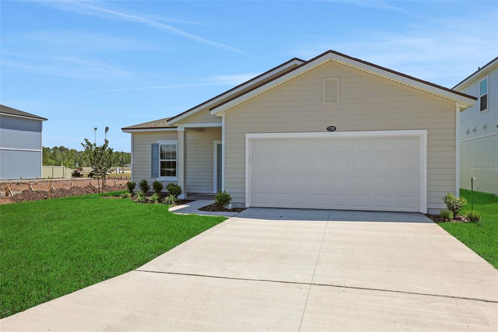 A single-story suburban house with beige siding, a two-car garage, and a concrete driveway — 5729 LAGOON CRUISE WAY, JACKSONVILLE, FL
