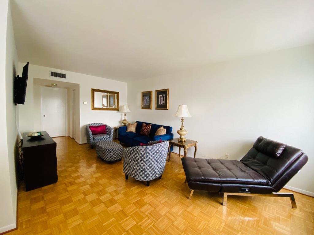 A living room features hardwood parquet flooring, a blue sofa, patterned armchairs, and a chaise lounge — 2840 Cynthia Lane # 203, FL 33461, FL