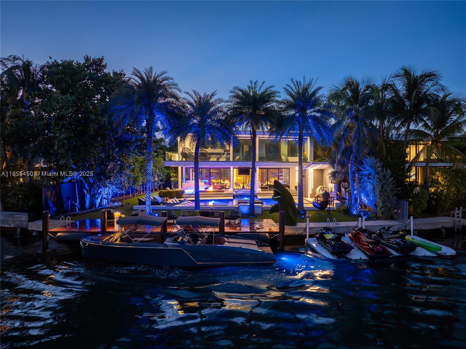 A modern waterfront home at night features a swimming pool, palm trees, and a boat dock — 528 Lakeview Ct, Miami Beach FL 33140, MIAMI BEACH, FL