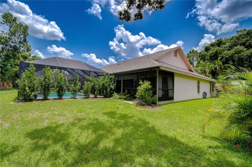 A backyard view of a house with a screened-in pool and a grassy lawn — 16126 BELLE MEADE BOULEVARD, ODESSA, FL