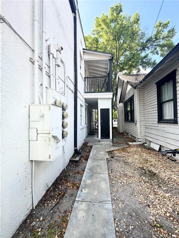 A narrow concrete walkway runs between a white stucco building and a white wood-sided house — 704 CORDOVA DRIVE UNIT 6, ORLANDO, FL