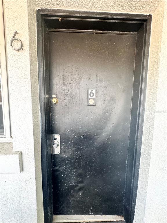 A black metal door with the number six is set into a textured exterior wall — 704 CORDOVA DRIVE UNIT 6, ORLANDO, FL