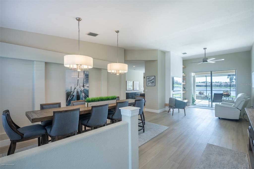 A dining area with a wooden table and blue chairs opens into a living space — 6571 TALON BAY DRIVE, NORTH PORT, FL