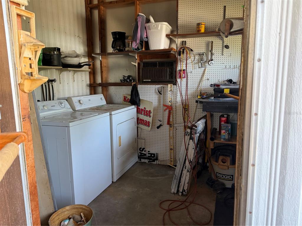 A laundry area features a white washer and dryer next to a pegboard storage wall — 8109 LITTLE TEE LANE, BROOKSVILLE, FL