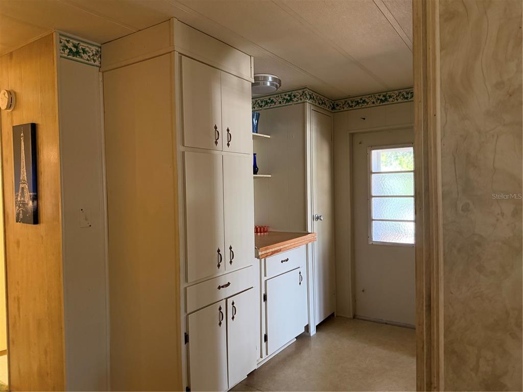 A kitchen features white cabinets, a wood-trimmed countertop, and a door with glass panels — 8109 LITTLE TEE LANE, BROOKSVILLE, FL
