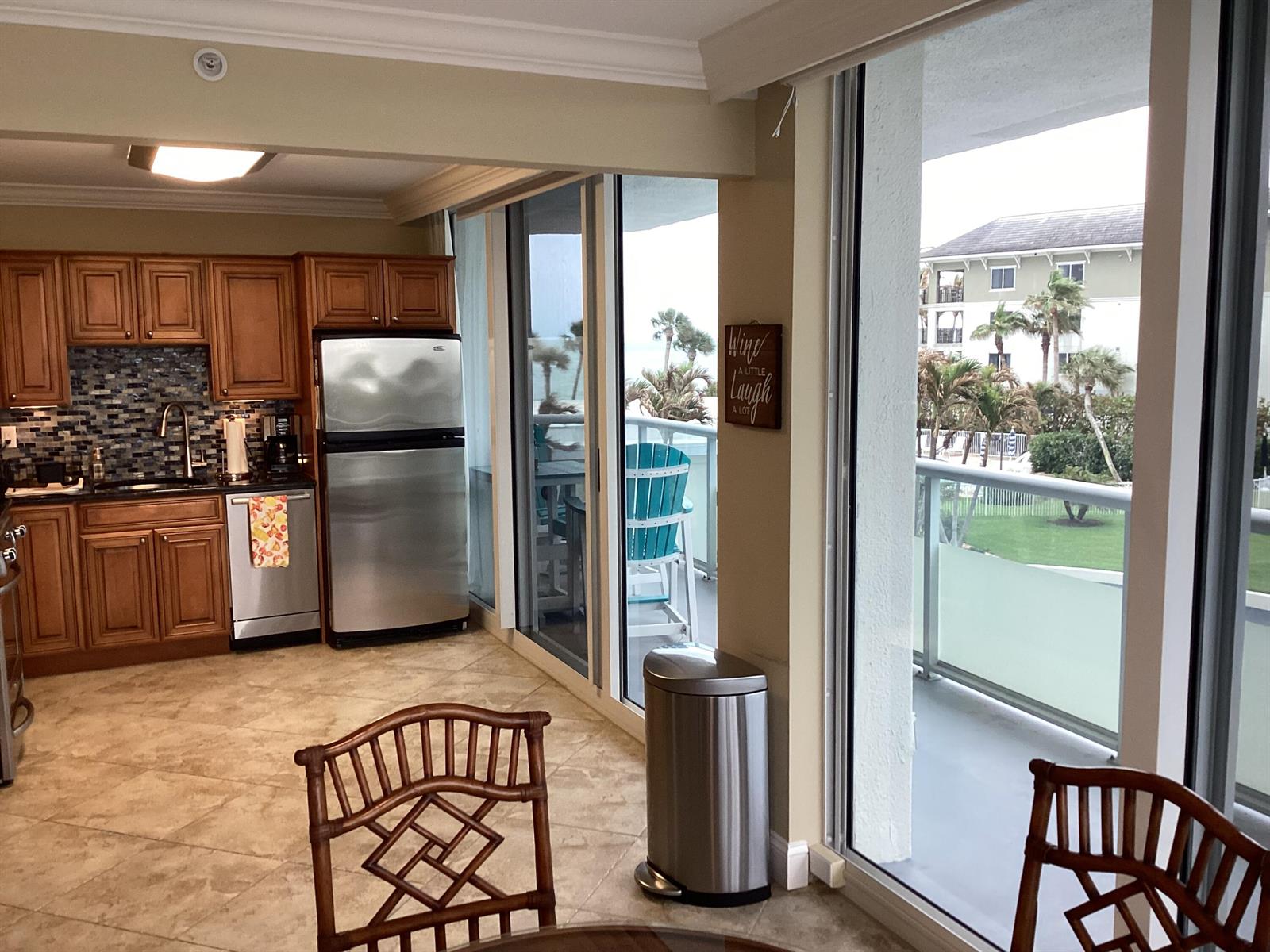 A kitchen with wood cabinets and stainless steel appliances opens to a balcony with views — 3554 Ocean Drive # 301, Vero Beach FL 32963, VERO BEACH, FL
