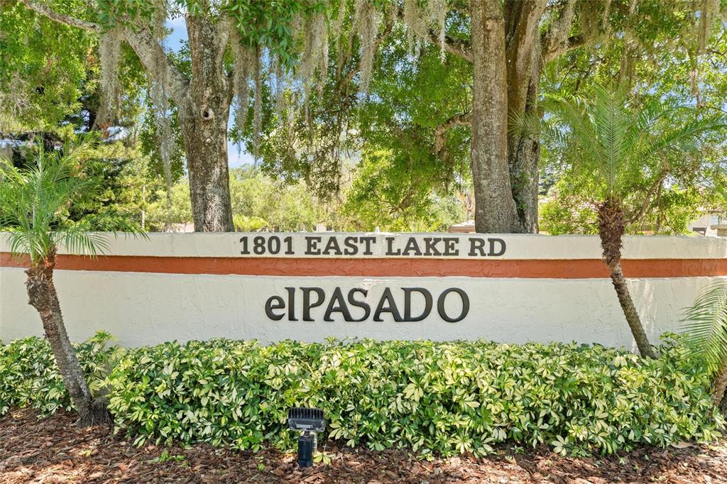 A sign for the El Pasado community stands in front of trees and landscaping — 1801 E LAKE ROAD UNIT 4E, PALM HARBOR, FL