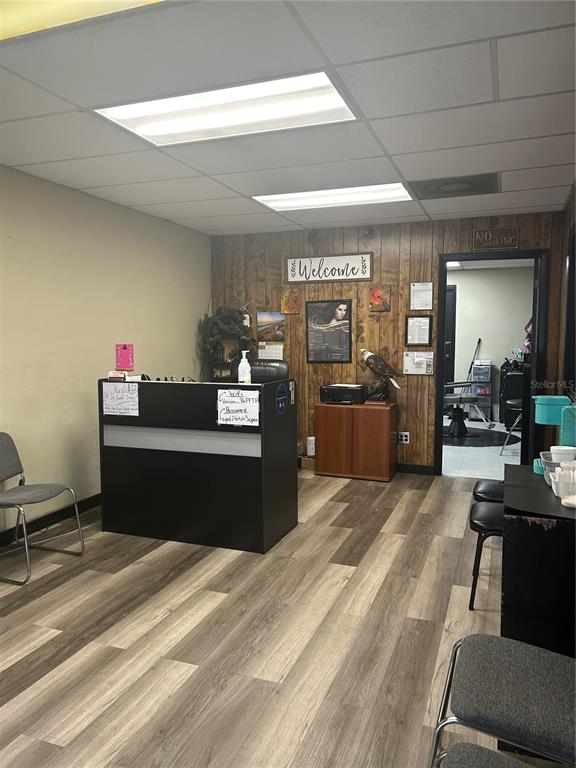 A reception area features a black desk, wood-paneled wall, and wood-look flooring — 1605 N TEMPLE AVENUE, STARKE, FL