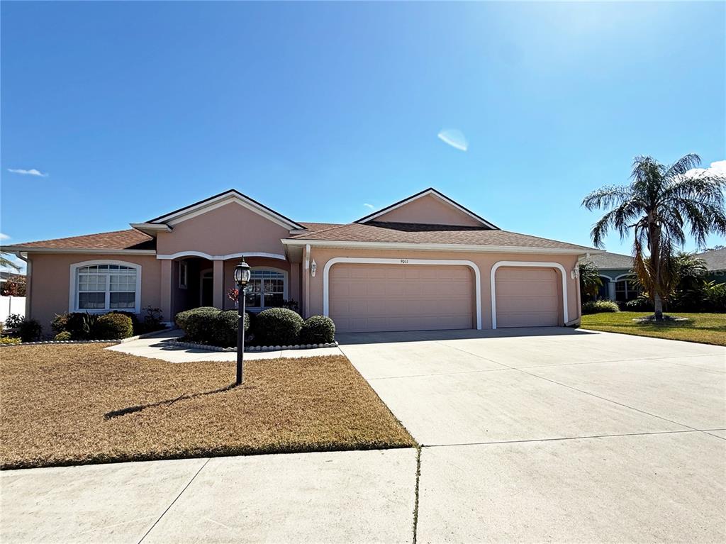 A single-story house with a peach-colored exterior, a three-car garage, and a concrete driveway — 9011 PROVINCE STREET, SARASOTA, FL