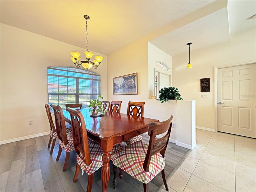A dining room features a wooden table with plaid chairs, a chandelier, and tile flooring — 9011 PROVINCE STREET, SARASOTA, FL