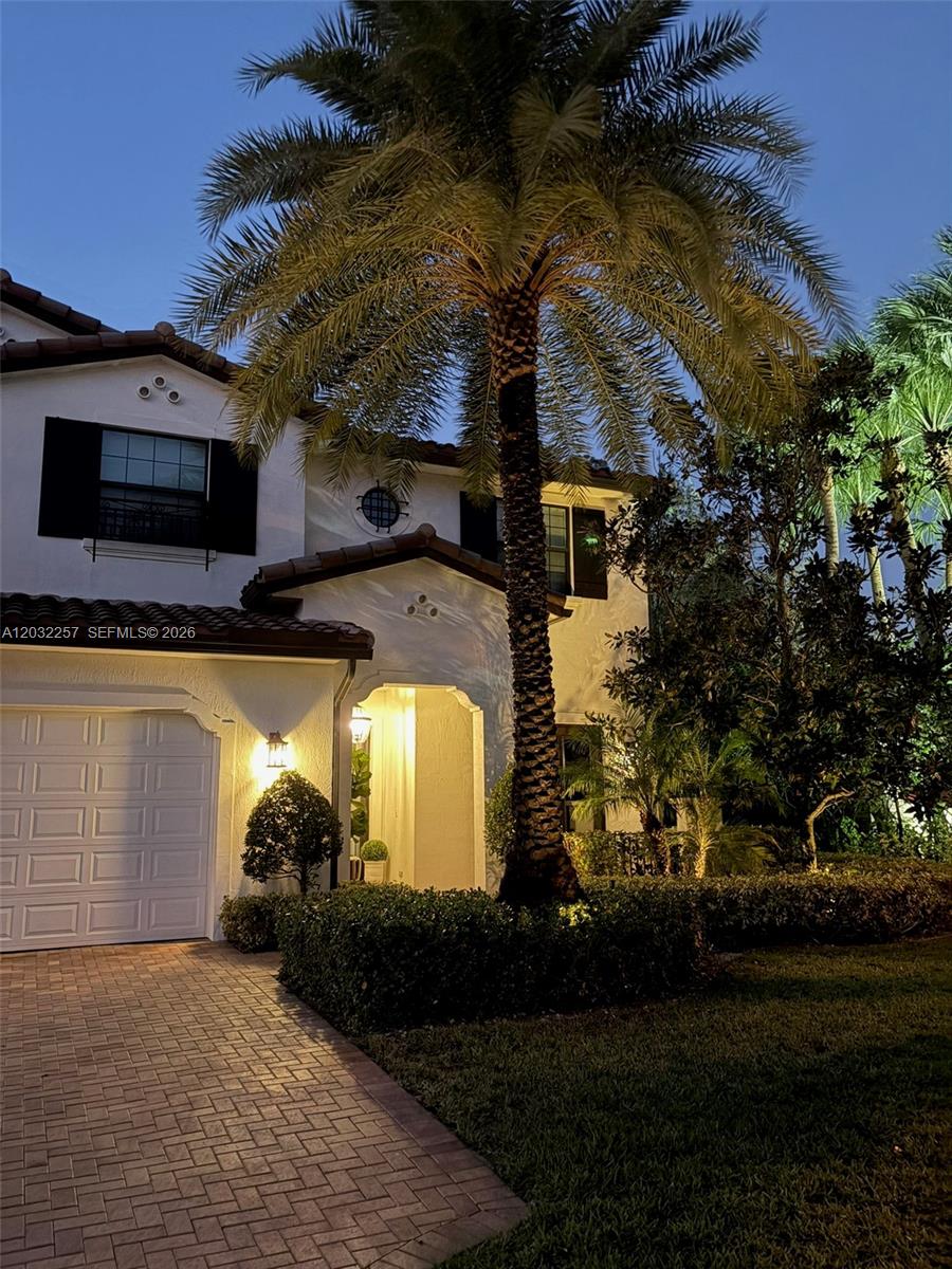 A two-story house exterior features a palm tree, paved driveway, and garage at dusk — 10609 SW 55th St, Cooper City FL 33328, COOPER CITY, FL