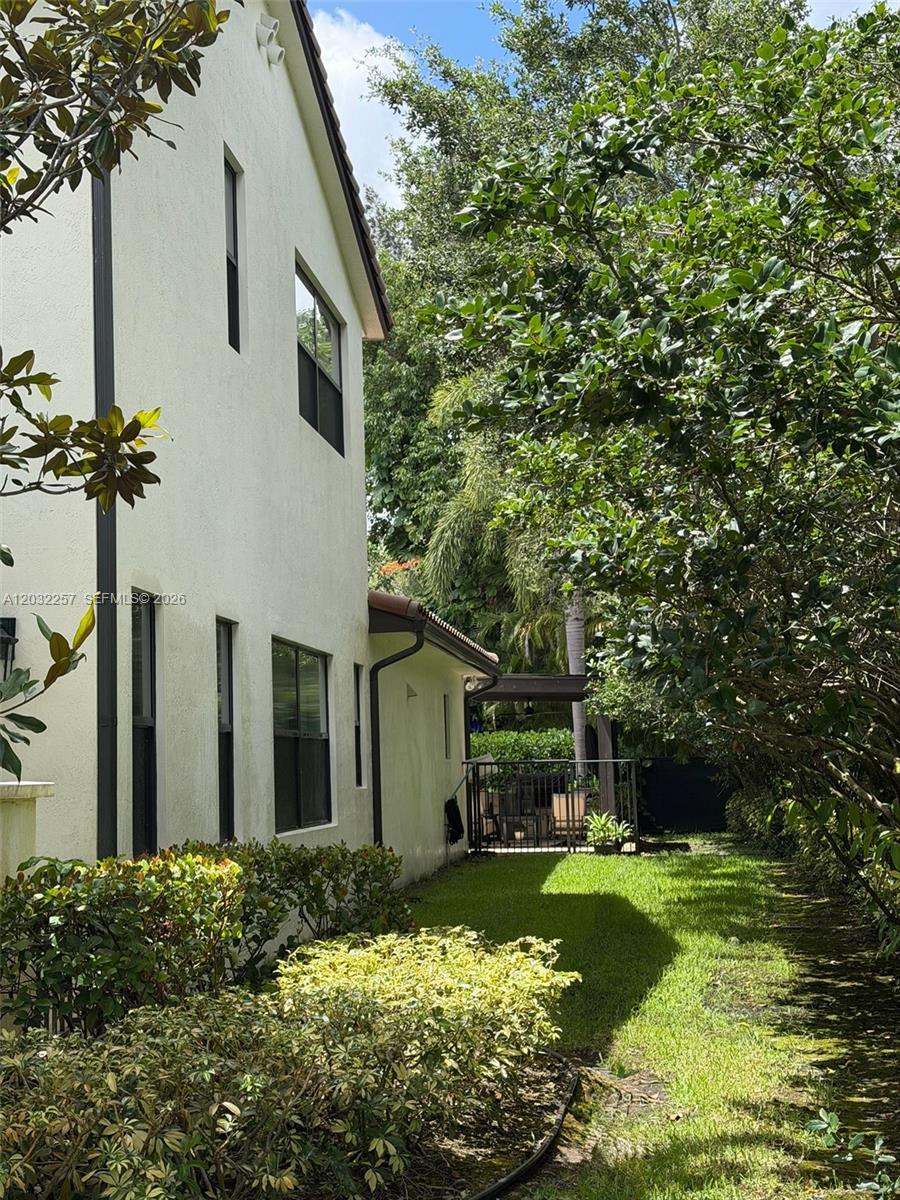 A side view of a two-story stucco house with a lawn and patio area — 10609 SW 55th St, Cooper City FL 33328, COOPER CITY, FL