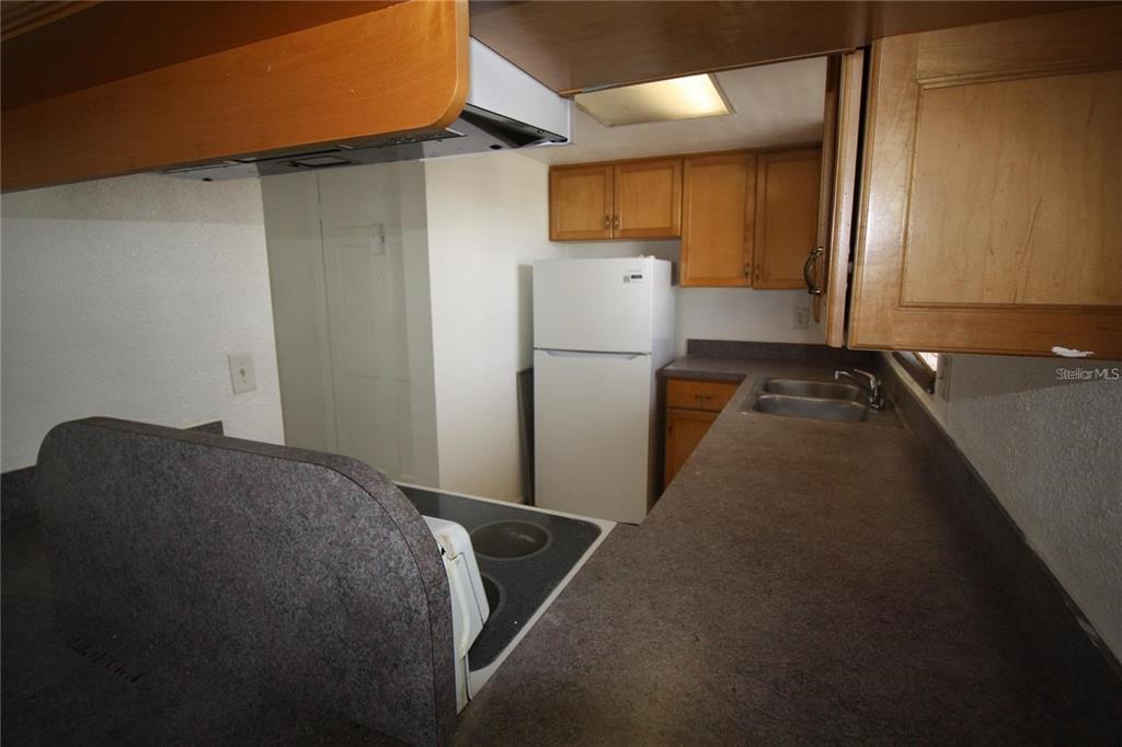 A kitchen features wooden cabinets, a white refrigerator, a stove, and a gray countertop — 1000 S SEMORAN BOULEVARD UNIT 306, WINTER PARK, FL