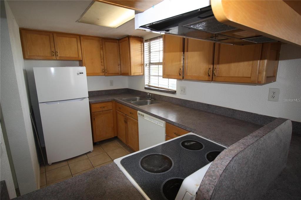 A kitchen features wood cabinets, white appliances, and dark laminate countertops — 1000 S SEMORAN BOULEVARD UNIT 306, WINTER PARK, FL