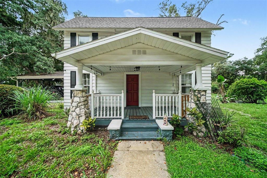A two-story white house with a front porch, stone pillars, and a red front door — 1509 W WINDHORST ROAD, BRANDON, FL