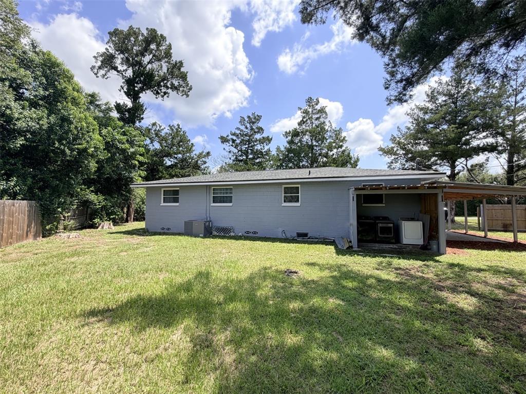 The rear exterior of a gray, single-story house features a small covered patio area — 1025 NE 4TH STREET, CHIEFLAND, FL
