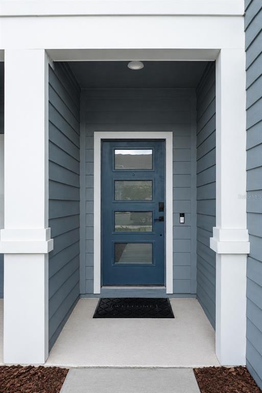 A blue front door with four glass panels is set within a covered entryway — 1730 DELIGHTFUL DRIVE, DAVENPORT, FL