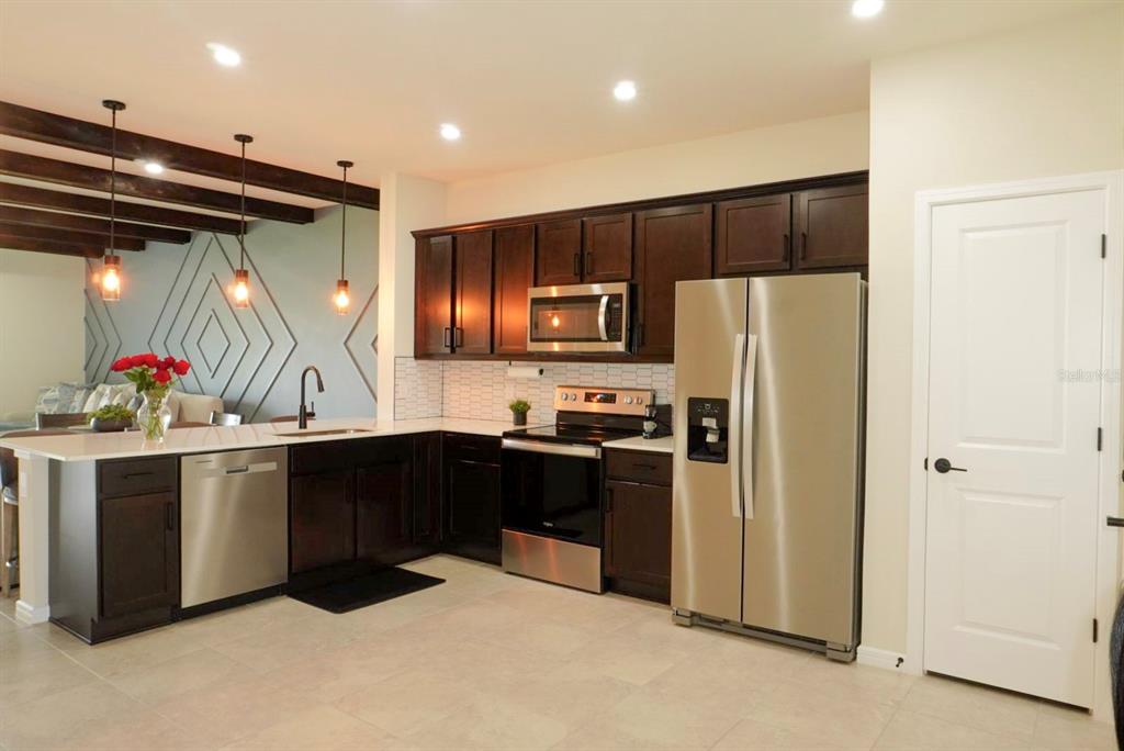 A kitchen features dark wood cabinets, stainless steel appliances, and a white countertop island — 1730 DELIGHTFUL DRIVE, DAVENPORT, FL