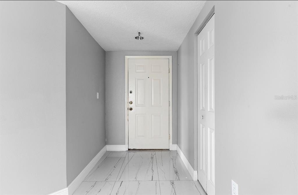 An entryway features light gray walls, white trim, and white marble-look tile flooring — 2725 TERRA CEIA BAY BOULEVARD UNIT 201, PALMETTO, FL