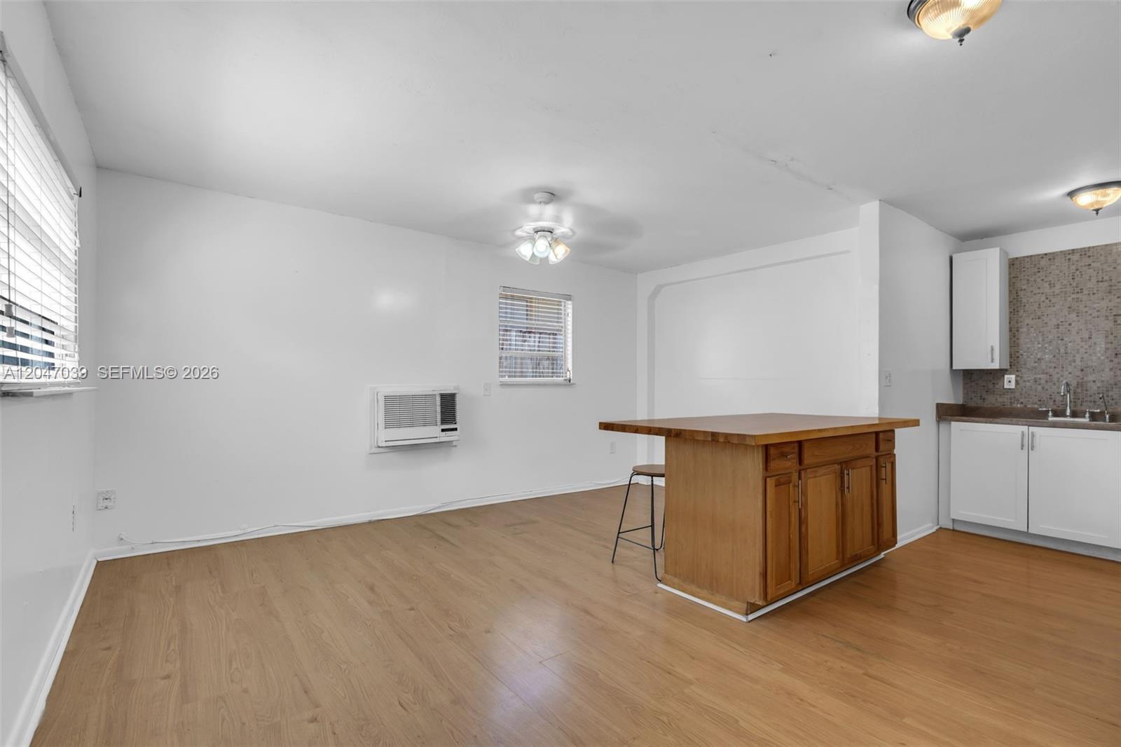 A kitchen and dining area features white walls, wood-look flooring, and a wooden island — 2809 SW 23rd Ter # 2807, Miami FL 33145, MIAMI, FL