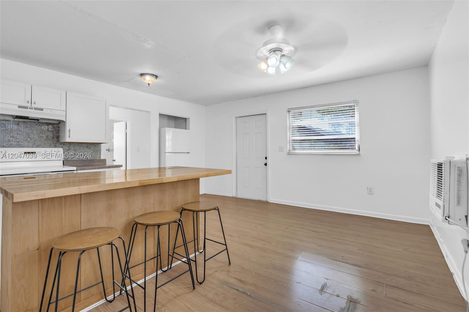 A kitchen with a wooden island and bar stools opens into a living area — 2809 SW 23rd Ter # 2807, Miami FL 33145, MIAMI, FL