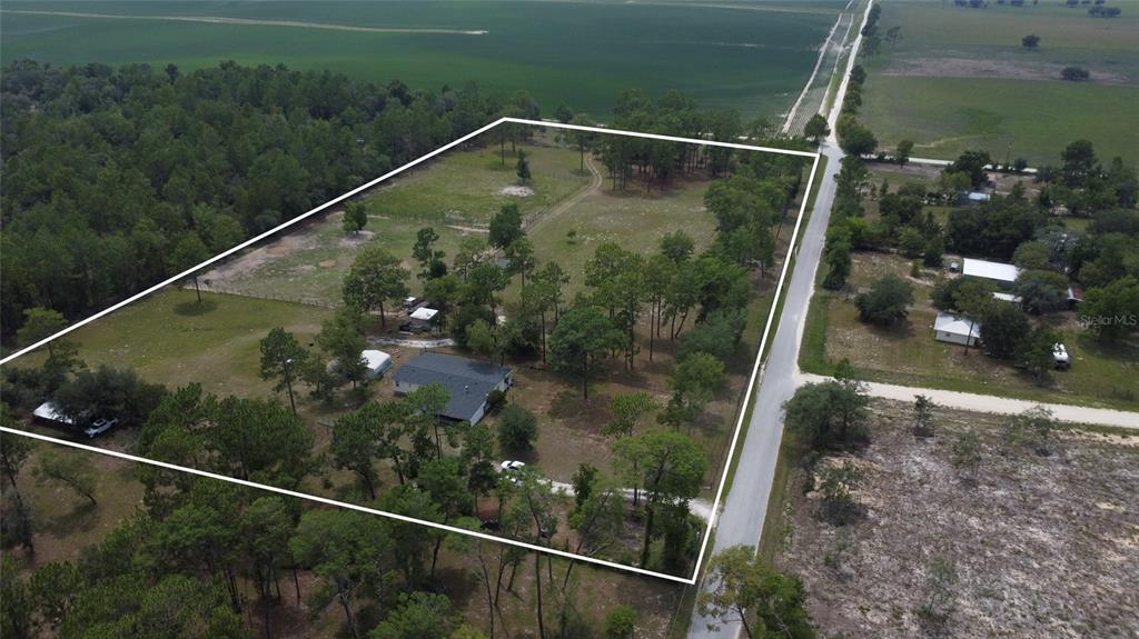 An aerial view shows a house situated on a large, fenced, tree-filled rural lot — 14050 SE 10TH STREET, WILLISTON, FL
