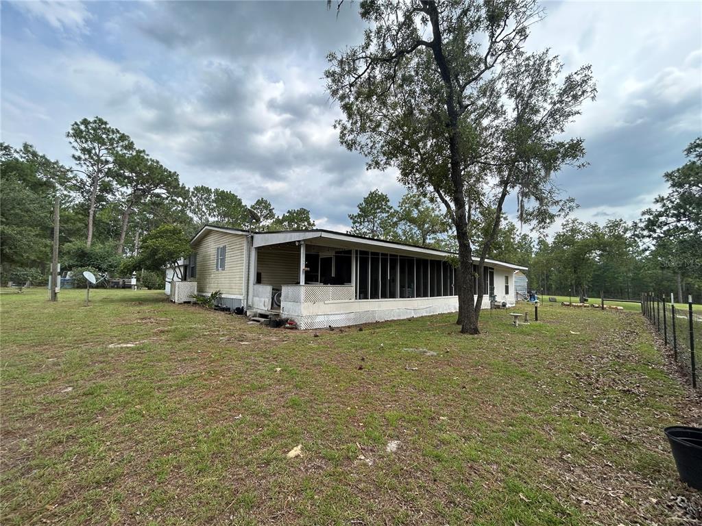 A single-story manufactured home features a large screened-in porch and a metal roof — 14050 SE 10TH STREET, WILLISTON, FL