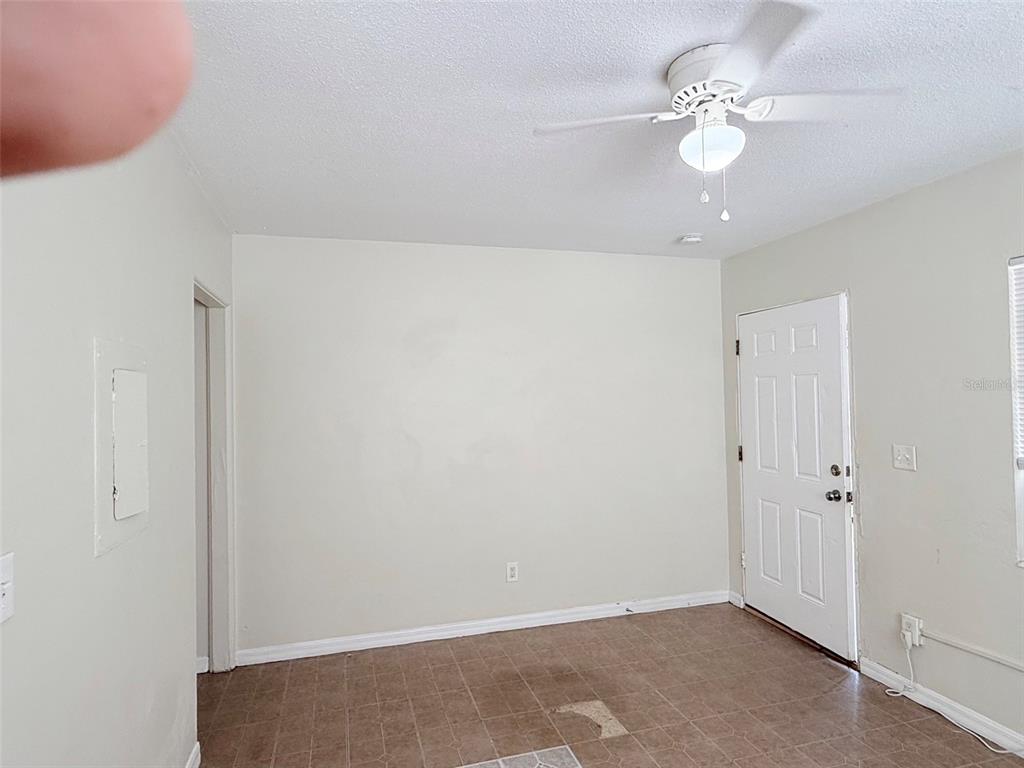 An empty room features light-colored walls, a ceiling fan, and brown tiled flooring — 2404 10TH STREET W UNIT 1, BRADENTON, FL