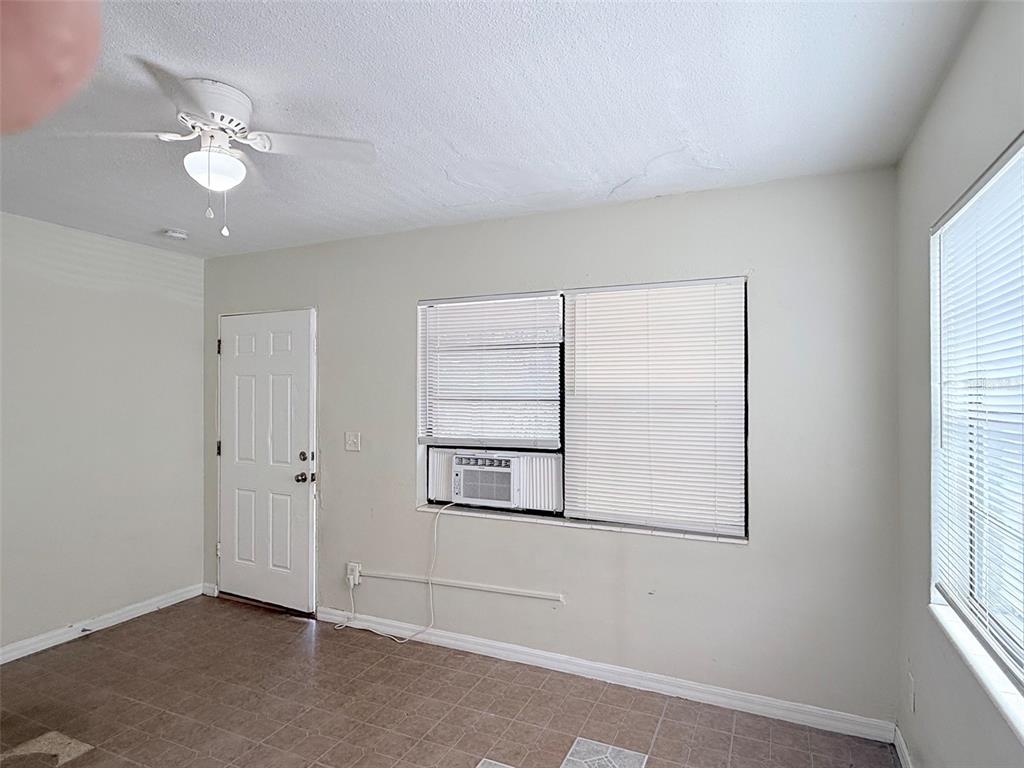 A room with tiled flooring, a ceiling fan, a white door, and a window air conditioner — 2404 10TH STREET W UNIT 1, BRADENTON, FL