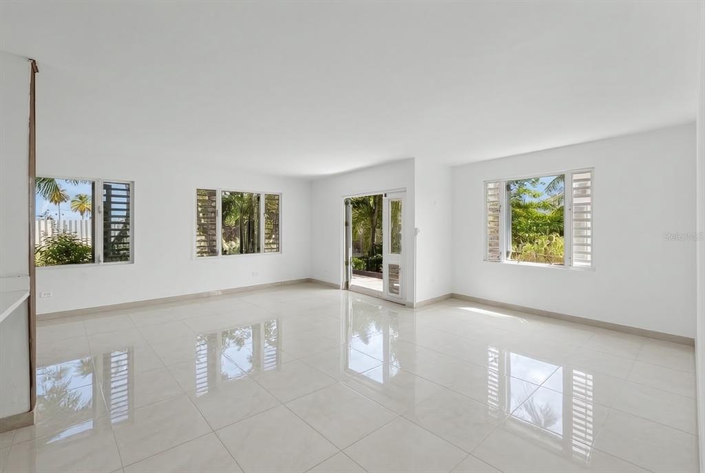 A paved driveway leads to a white two-story building with a gated entrance and landscaping — 3-B CALLE KENNEDY, DORADO, PR