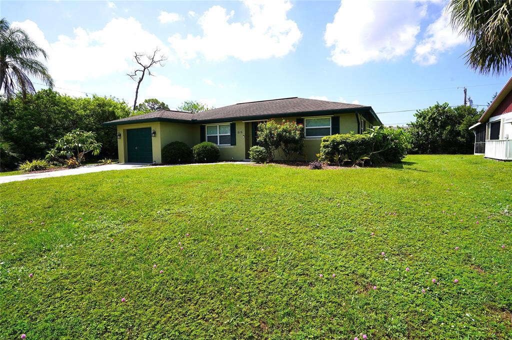 A single-story house with a green exterior, attached garage, and a large front lawn — 515 MERIDAN AVENUE NW, PORT CHARLOTTE, FL