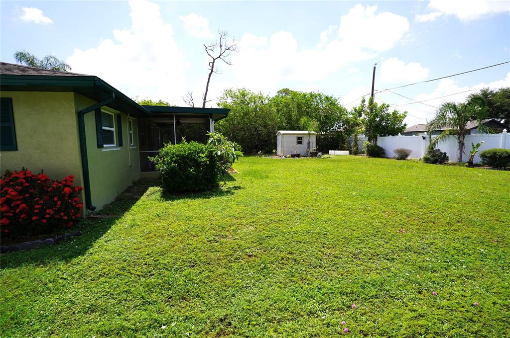A backyard features a house with a screened porch, a shed, and a white fence — 515 MERIDAN AVENUE NW, PORT CHARLOTTE, FL