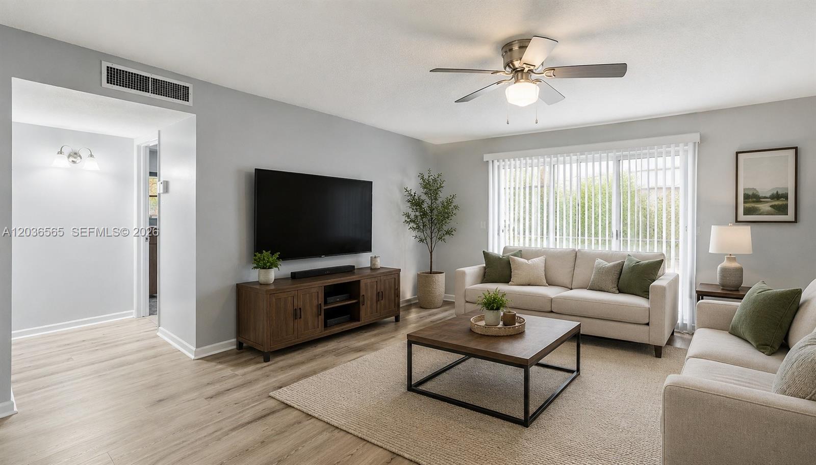 A living room features light gray walls, wood-look flooring, a ceiling fan, and neutral furniture — 306 S Circle Dr S # 104, Boynton Beach FL 33435, BOYNTON BEACH, FL
